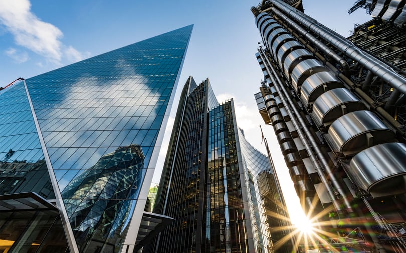 Low-angle view of modern glass and steel skyscrapers reflecting the sky in a major financial district.