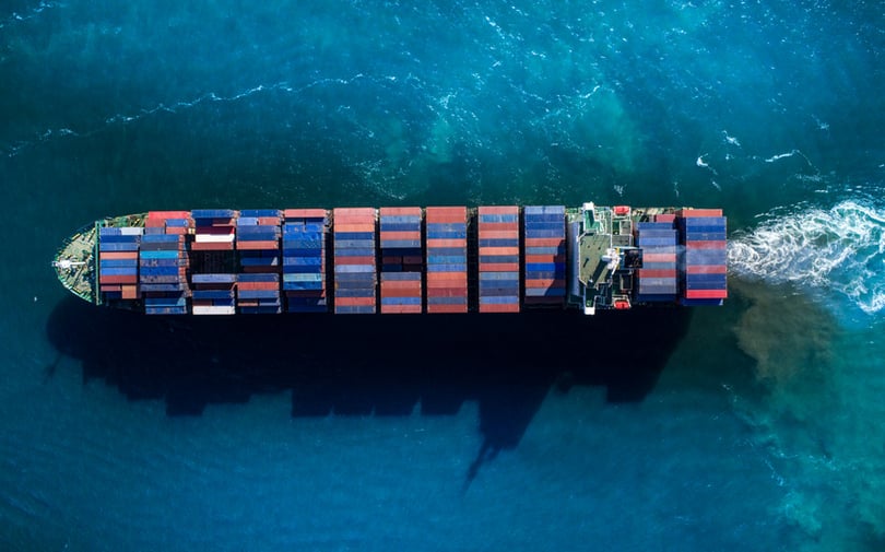 A large blue container ship carrying multi-colored freight across the ocean.